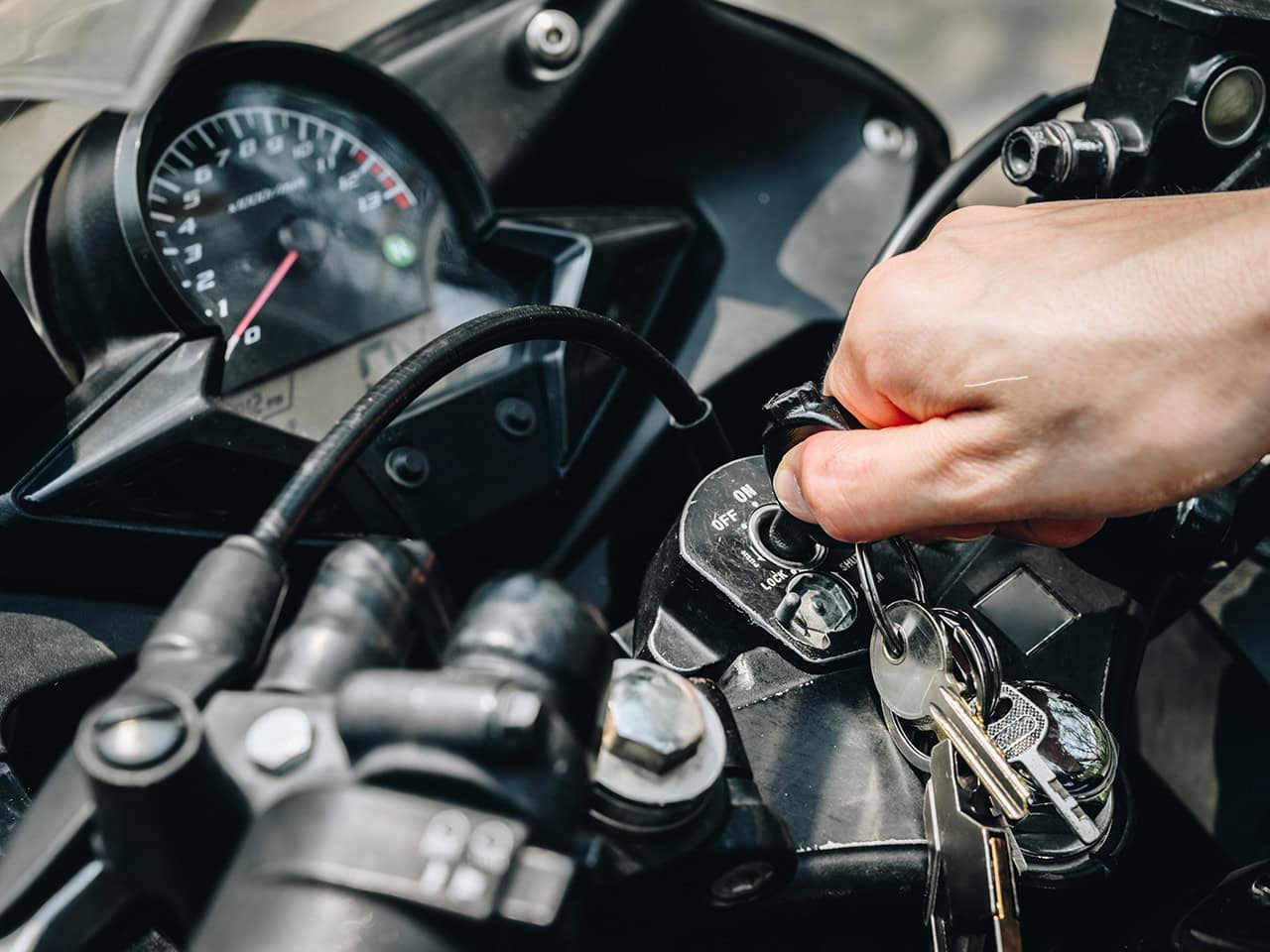 Man turning on a motorcycle with a key